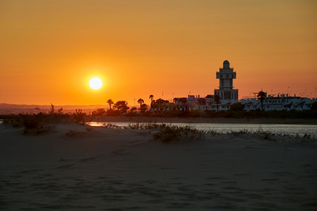The lighthouse of Isla Cristina on the beach of Playa de la Gaviotas in orange yellow sunset light, Andalusia, Spainの写真素材