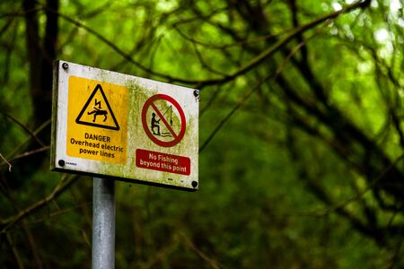 These warning sign are on a path leading through a wood to local fishing pond. They warn of overhead power lines.の写真素材