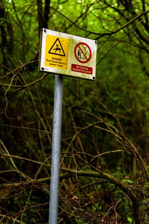 These warning sign are on a path leading through a wood to local fishing pond. They warn of overhead power lines.の写真素材