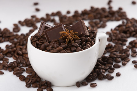 Capuccino cup filled with coffee beans, sweet chocolates and aniy starの写真素材