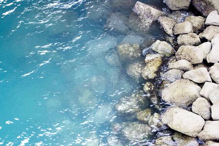 the water of the sea and some rocks in the shoreの写真素材