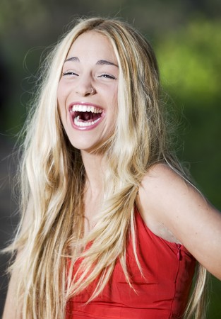 beautiful girl with a red dress in the nature laughing