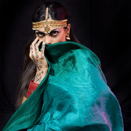 young beautiful oriental style woman covering herself with a green veil