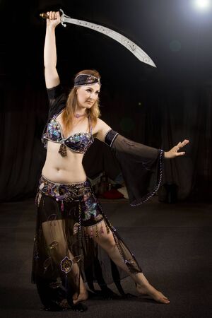 oriental woman dancing the typical belly dancing with a sabreの写真素材