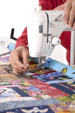 A woman quilter is pulling new thread through the sewing machine to begin quilting.