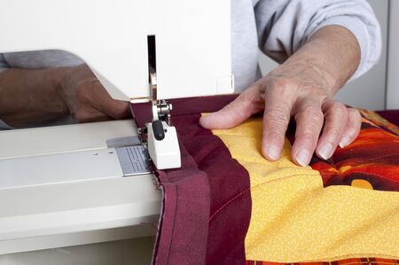 A quilter sews on binding to a quilt 