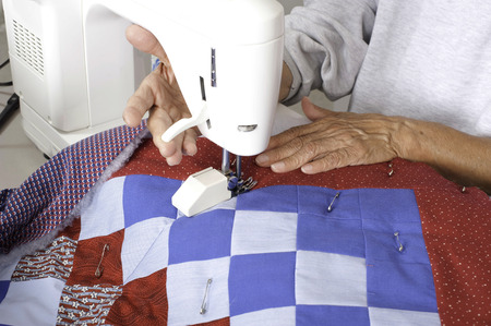 A female quilter lifting the walking foot lever after completing the grid pattern on a patriotic quilt.の写真素材