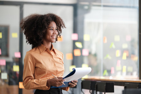 African American female employee write down on colorful sticky notes manage list, concentrated...