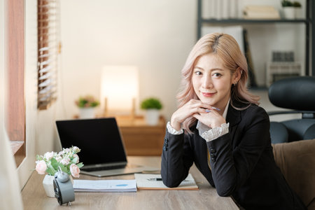Close up on laptop in office, Asian happy beautiful businesswoman in formal suit work in workplace. Attractive female employee office worker smile.の写真素材
