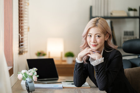 Close up on laptop in office, Asian happy beautiful businesswoman in formal suit work in workplace. Attractive female employee office worker smile.の写真素材