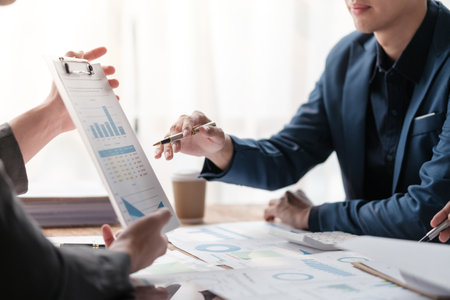 Close up group of business men and woman discussion and brainstorming, bookkeeping audit graph and chart documents at desk, teamwork concept.の写真素材
