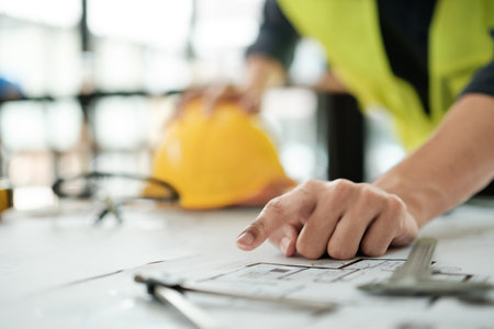 Close up of hands architects working on blueprints in the office with drawing tools and a blueprint on his desk.の写真素材