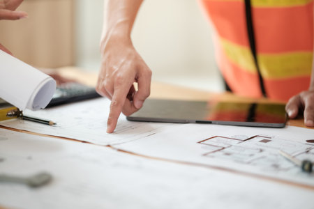 Close up of hands architects working on blueprints in the office with drawing tools and a blueprint on his desk.の写真素材