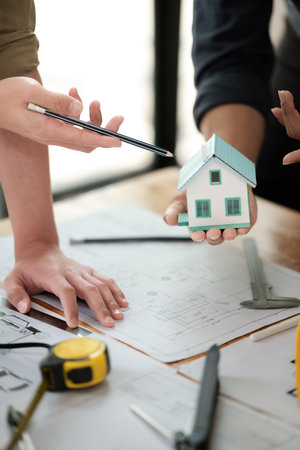 Engineers consulting team close up to design building blueprints paper for clients with building models to work at office.の写真素材