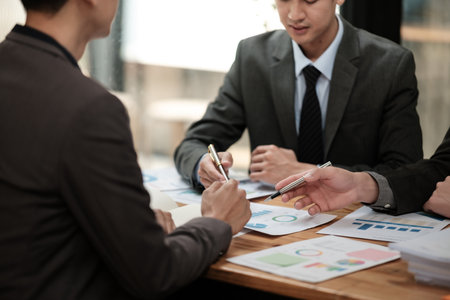 Close up group of business men and woman discussion and brainstorming, bookkeeping audit graph and chart documents at desk, teamwork concept.の写真素材