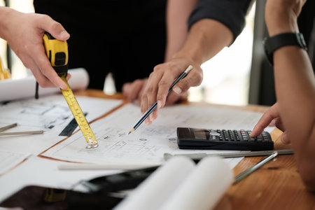 Close up of hands architects working on blueprints in the office with drawing tools and a blueprint on his desk.の写真素材