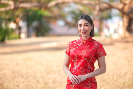 Asian woman in red cheongsam qipao dress holding lantern while visiting the Chinese Buddhist temple...