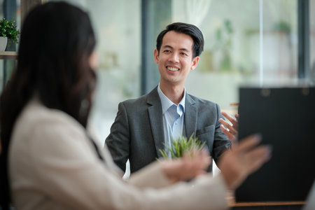Two business workers smiling happy working sitting on desk at the office.の写真素材
