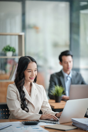 Two business workers smiling happy working sitting on desk at the office.の写真素材