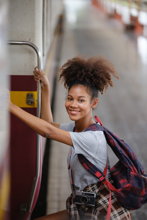 Young Asian African woman traveler with backpack in the railway train station, traveler girl walking...