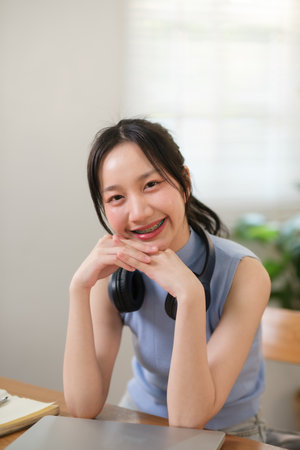 Young attractive happy asian female student sitting at living room floor smiling and looking up at camera working on laptop at home office. Young startup entrepreneur or freelance business concept.の写真素材