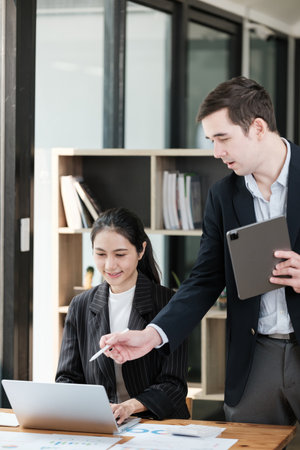 A man and a woman are standing in front of a desk with a laptop and a tabletの写真素材