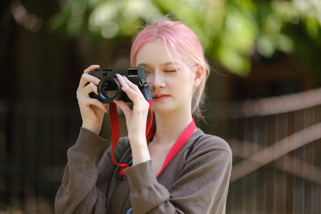 Beautiful Young artist Woman taking photo in flowers garden. Young cute girl carry the camera in the...
