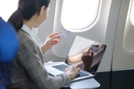 A woman is using a laptop to pay for a flightの写真素材