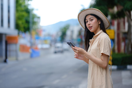 A woman wearing a hat and a dress is holding a cell phoneの写真素材
