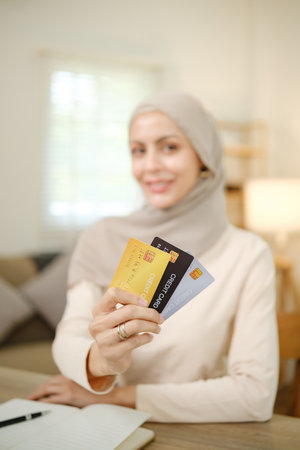 A woman is holding four credit cards in her hand