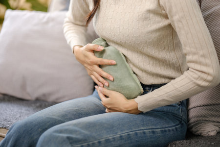 A woman is sitting on a couch with a green cloth in her handの写真素材