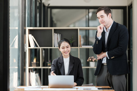 A man and a woman are standing in front of a desk with a laptopの写真素材