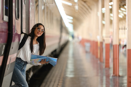 A woman is standing on a train platform with a map in her handの写真素材