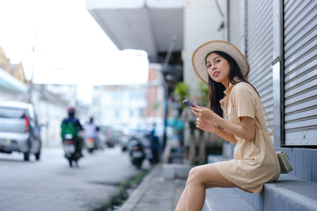 A woman in a yellow dress is sitting on a step with her cell phone in her handの写真素材