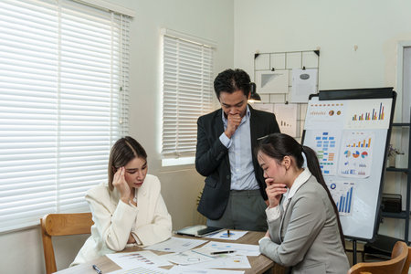 Three people are sitting at a table with papers in front of themの写真素材
