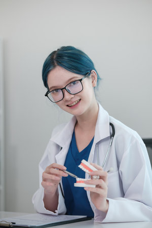 A woman in a white lab coat holding a pair of teeth