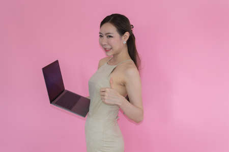 Women are playing a notebook on pink backgroundの写真素材