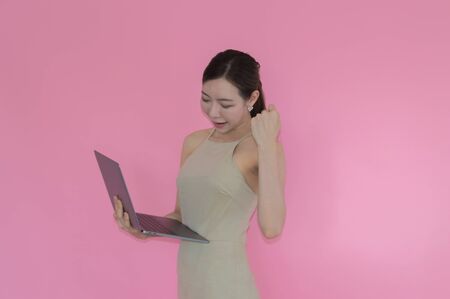 Women are playing a notebook on pink backgroundの写真素材