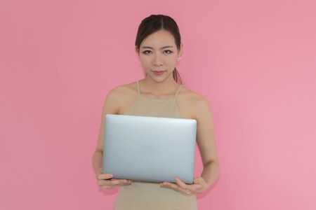 Women are playing a notebook on pink backgroundの写真素材