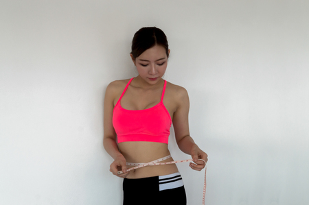 woman measures the waist his on white backgroundの写真素材