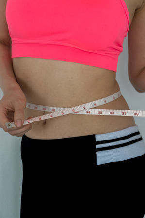 woman measures the waist his on white backgroundの写真素材