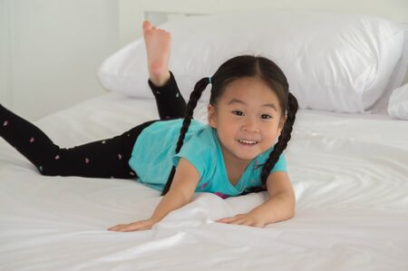 The girl plays in bed in a white bedroom.の写真素材