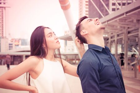 The girl is pulling the hair of a young man.の写真素材