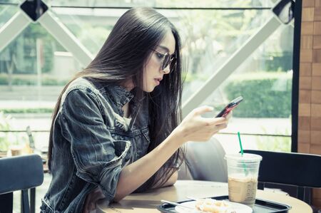 The girl is playing mobile in a cafe.