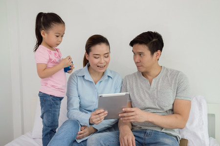 Parents and children are playing the tablet happily.の写真素材