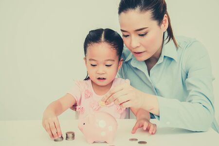 Daughter and mother are coin piggy bank.の写真素材
