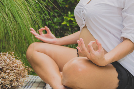 Pregnant women are playing yoga in the garden.の写真素材