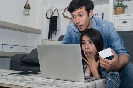 Young man using laptop and woman with happy emotion at living room.の写真素材