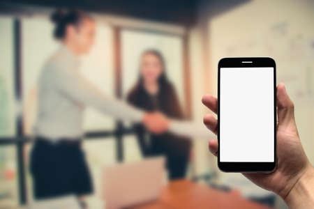 Hold  mobile on the background of a group of business people working in an office.の写真素材