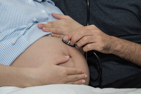 Men listen to pregnant women with a happy home mood.の写真素材